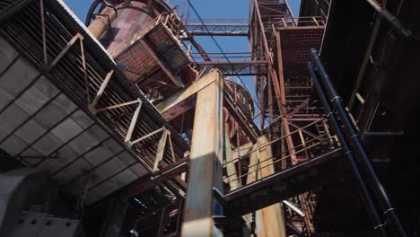 Abandoned-buildings,-with-broken-windows,-crumbling-walls-and-rusted-metal-structures-of-industrial-complex