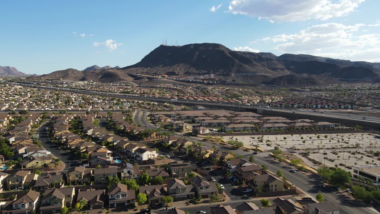 drone ascendiendo sobre los suburbios en henderson nevada con carretera y montañas en el cielo azul de fondo 60fps