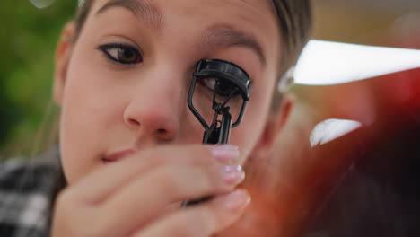 close-up view of young lady using eyelash curler to fix eyelashes, carefully shaping them for a precise beauty look, highlighting makeup tools and techniques for flawless results