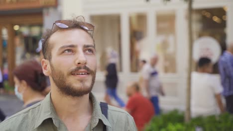 joven mirando a su alrededor en una calle llena de gente.