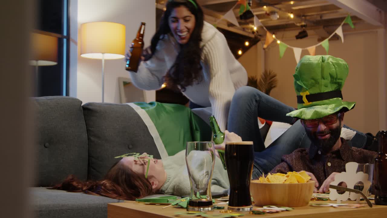 친구 그룹이 집이나 술집에서 아일랜드의 새로움과 재료로 옷을 입고 세인트 패트릭의 날 파티 2에서 축하합니다.