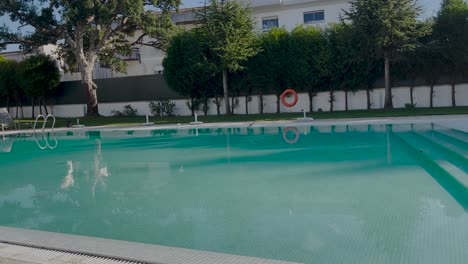 Zooming-in-on-an-empty-swimming-pool-with-birds-in-motion-flying-above