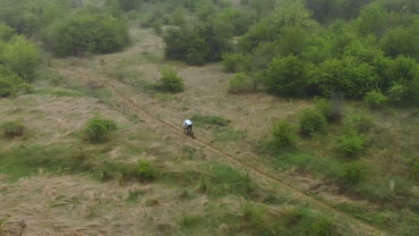 Toma-Aérea-De-Un-Ciclista-De-Montaña-Rápido-En-Un-Camino-Pequeño