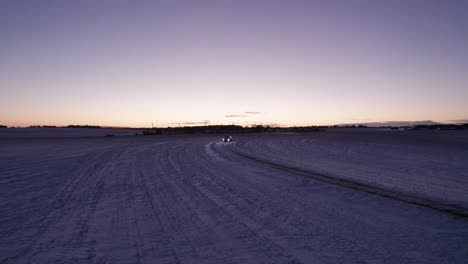 bird's eye view of car driving on a snowy road in a winter landscape, scandinavia - panning shot