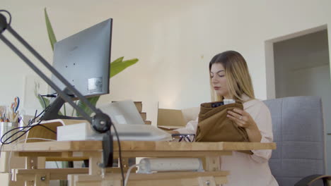 blonde caucasian woman checking clothing label and putting in box