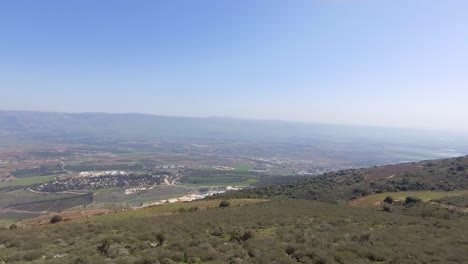 huge valley with a town at the bottom exposed and hermon mountain in the background