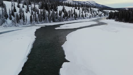 takhini river flowing through snowy landscape in winter in yukon, canada. drone shot