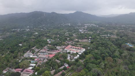 Drone-flyover-small-town-surrounded-by-vegetation-toward-foggy-mountain-range,-Palomino