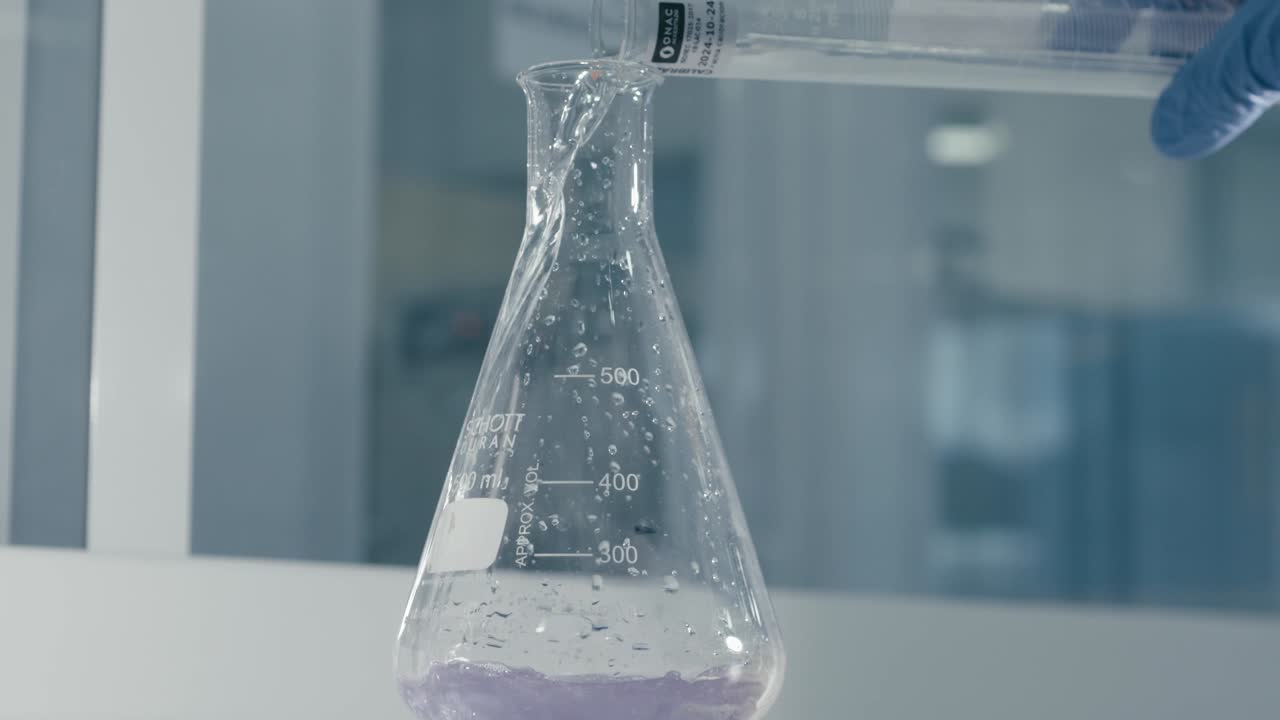 Lab worker's hand pouring serum liquid into test tube while working in Medical Drug Production
