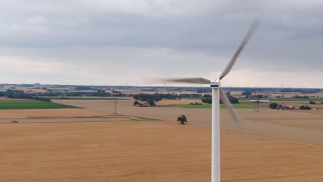 toma amplia de drones que muestra vastos campos y agricultura con turbina eólica en primer plano