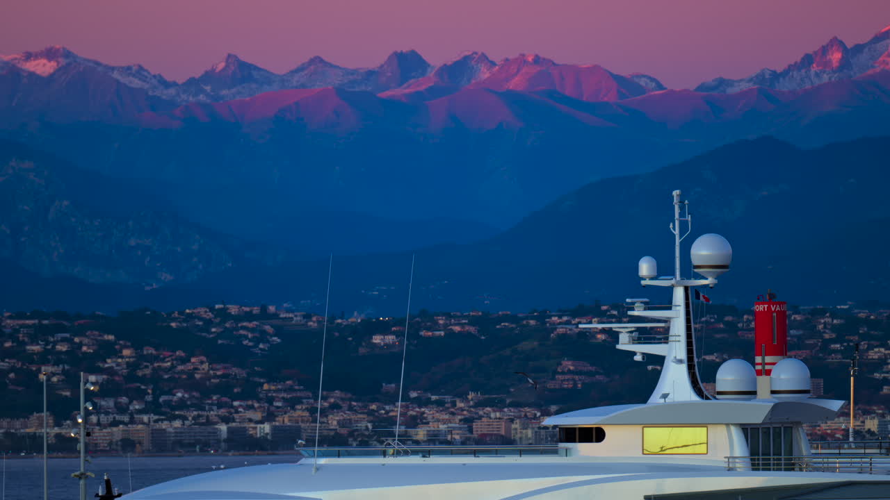 Multiple white boats docked in the Port Vauban, Antibes, France with the mountains on the background at sunset