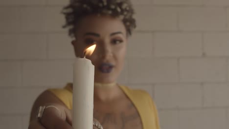 black beautiful female with yellow shirt holding white lit candle near camera