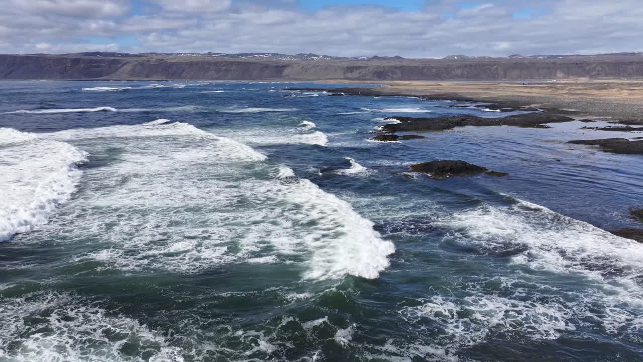 el video captura la belleza del paisaje islandés con una foto amplia del océano y una pequeña isla en la distancia