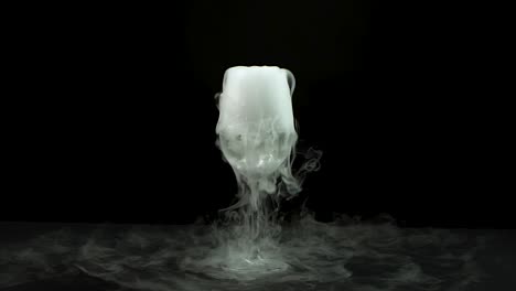 water in wine glass with the effect of dry ice. slow motion - water in wine glass with the effect of dry ice on black background at studio. slow motion