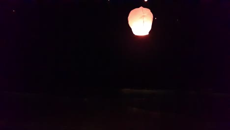 woman releases a fire sky lantern in the air at night