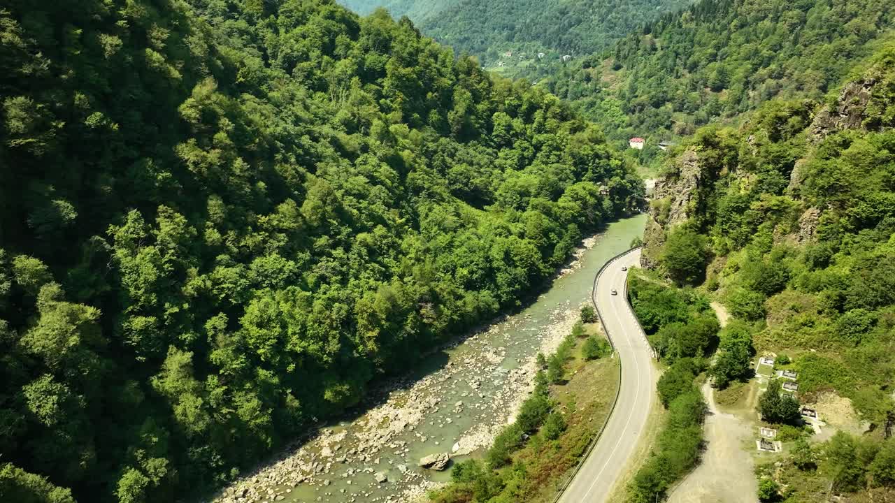 A long winding path running through a deep forest valley near a flowing river