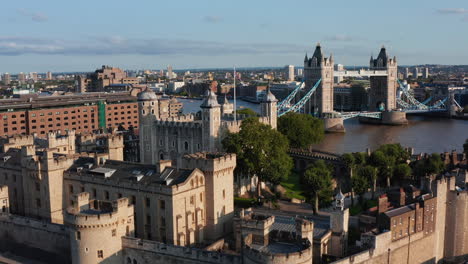 Forwards-fly-above-Tower-of-London-in-golden-hour.-Impressive-stone-fortification-of-medieval-castle.-Old-White-Tower-with-four-corner-towers-and-Union-Jack-on-pole.-London,-UK