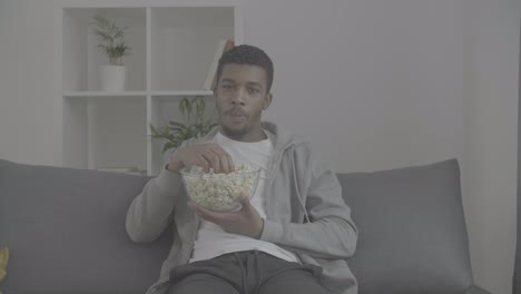 young african american male looking directly at the camera and showing us a popcorn