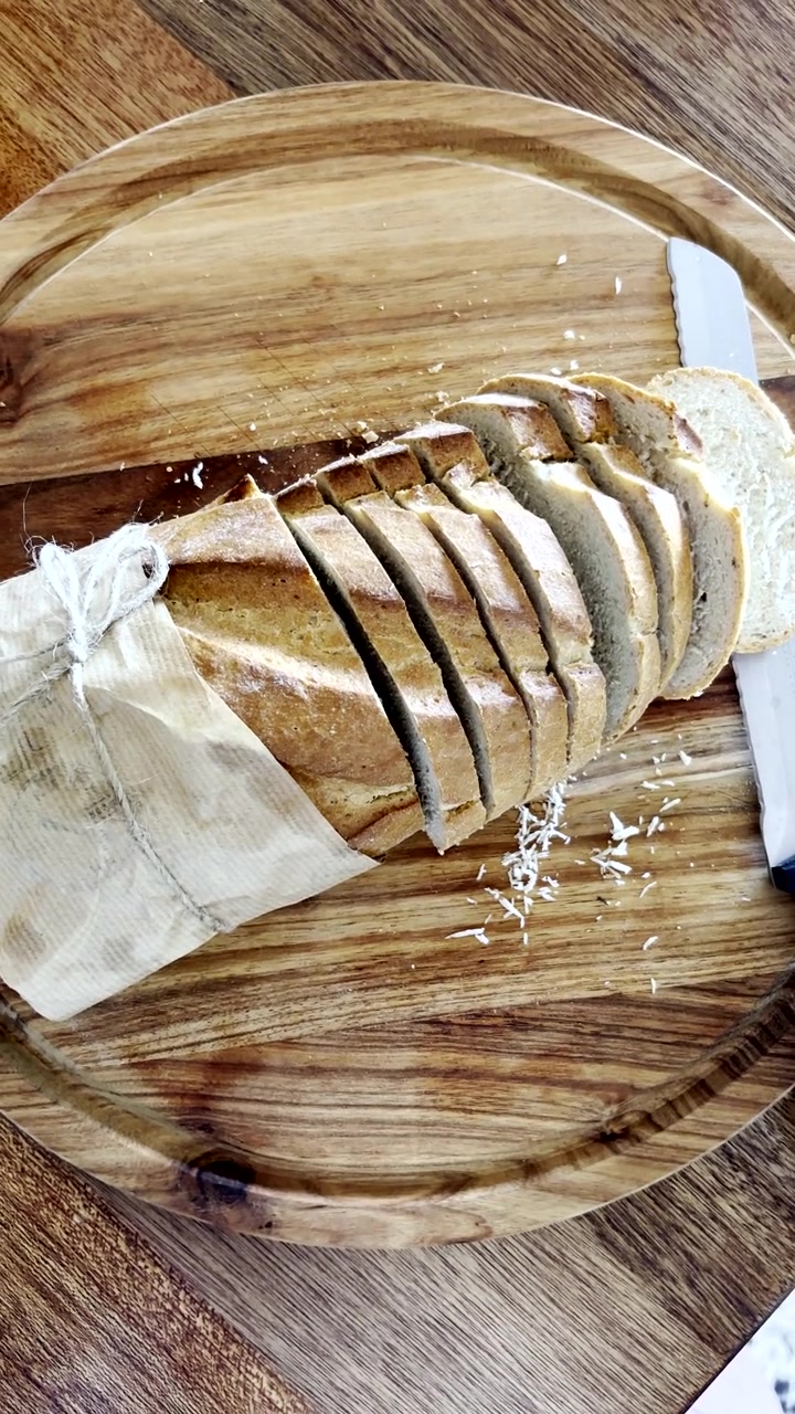 Pane fatto in casa con fette e coltello su un tagliere di legno. Verticale.