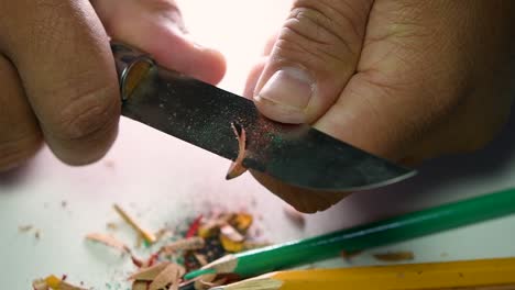 Footage-of-hands-slowly-sharpening-a-pencil-and-some-coloured-pencils-with-a-sharp-knife