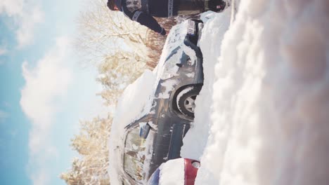 Vertikale-Aufnahme-Eines-Mannes,-Der-Schnee-Vom-Auto-Wischt,-Während-Sein-Glücklicher-Hund-Neben-Ihm-Springt-Und-Den-Schnee-Auffängt,-In-Trondheim,-Norwegen