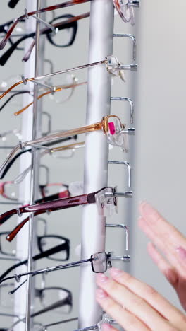 woman choosing eyeglasses. close up of female trying glasses at shop store