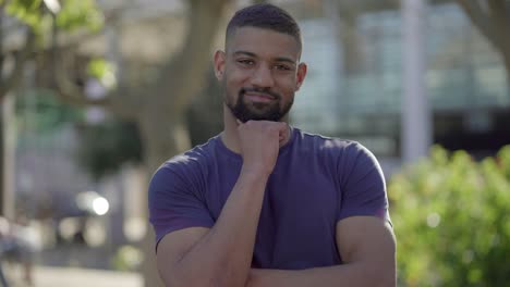 man standing in park with hand under chin, looking at camera