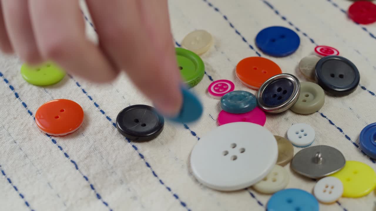 bottoni colorati che cadono su tessuto a righe in primo piano. abiti da sartoria e concetto di cucito professionale. scelta di accessori a bottoni per il materiale
