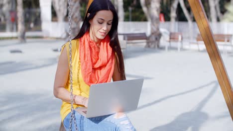 mujer joven con una computadora portátil en un parque