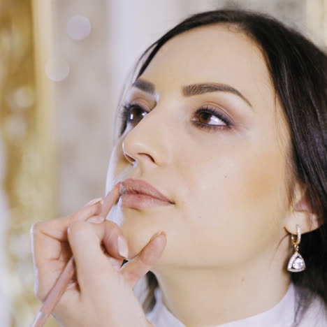 an experienced master draws the contour of a brunette's lips with a pink pencil before applying the pigment to the lips in the cosmetology center. permanent makeup. close-up.