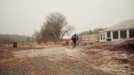 man carrying piece of wood into greenhouse under construction