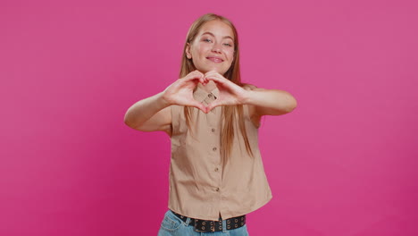 smiling pretty woman makes heart gesture demonstrates love sign expresses good feelings and sympathy