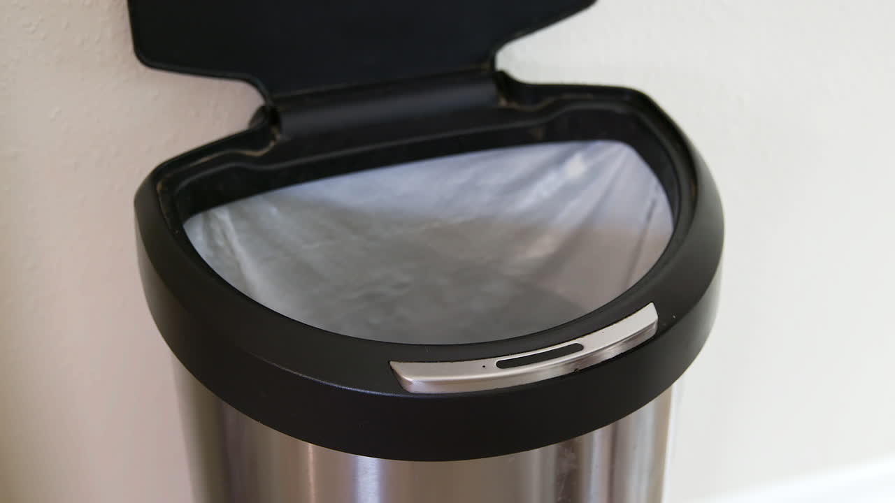 사람이 터치리스 쓰레기통을 감지하고 동작 중에 바나나 껍질을 버립니다 - 위 가까이