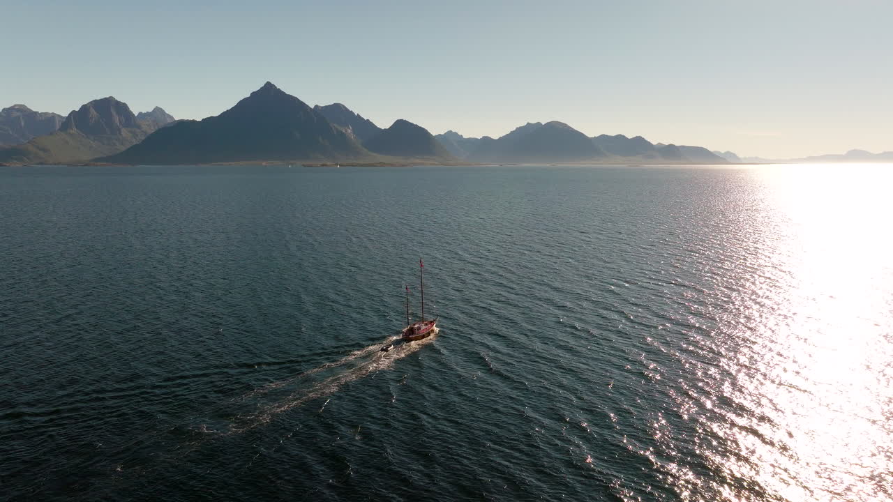 Barca a vela che naviga in mare aperto nelle isole Lofoten al tramonto, vista aerea