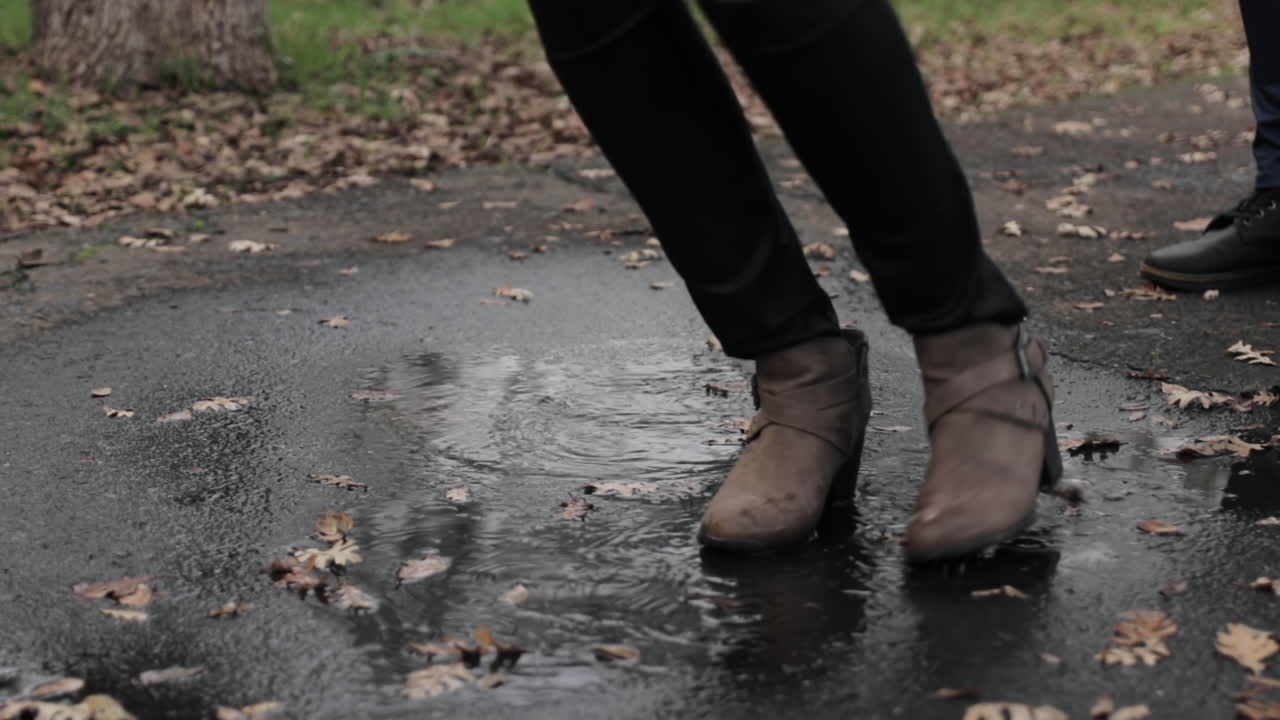 Young woman's feet splash across puddle toward camera, slow motion, close up