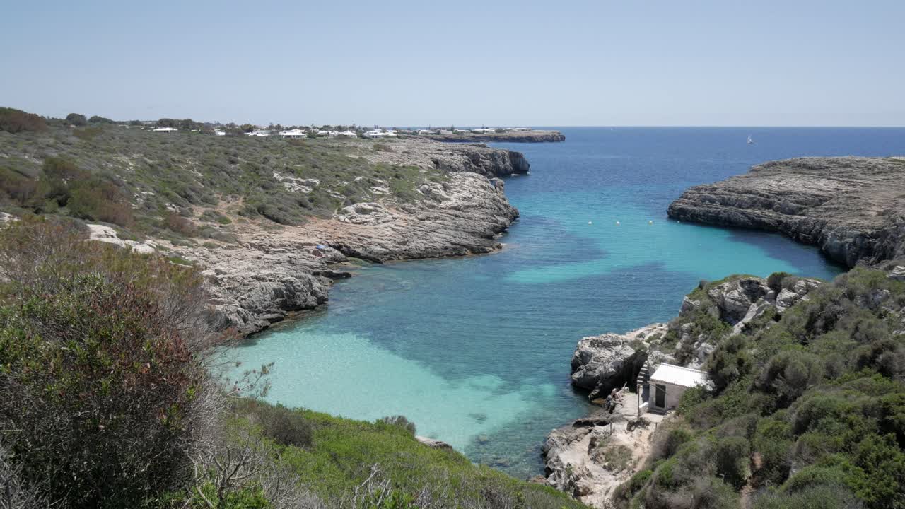 A beautiful view of Cala Binidali beach in Menorca, showcasing crystal-clear waters and rocky coastline
