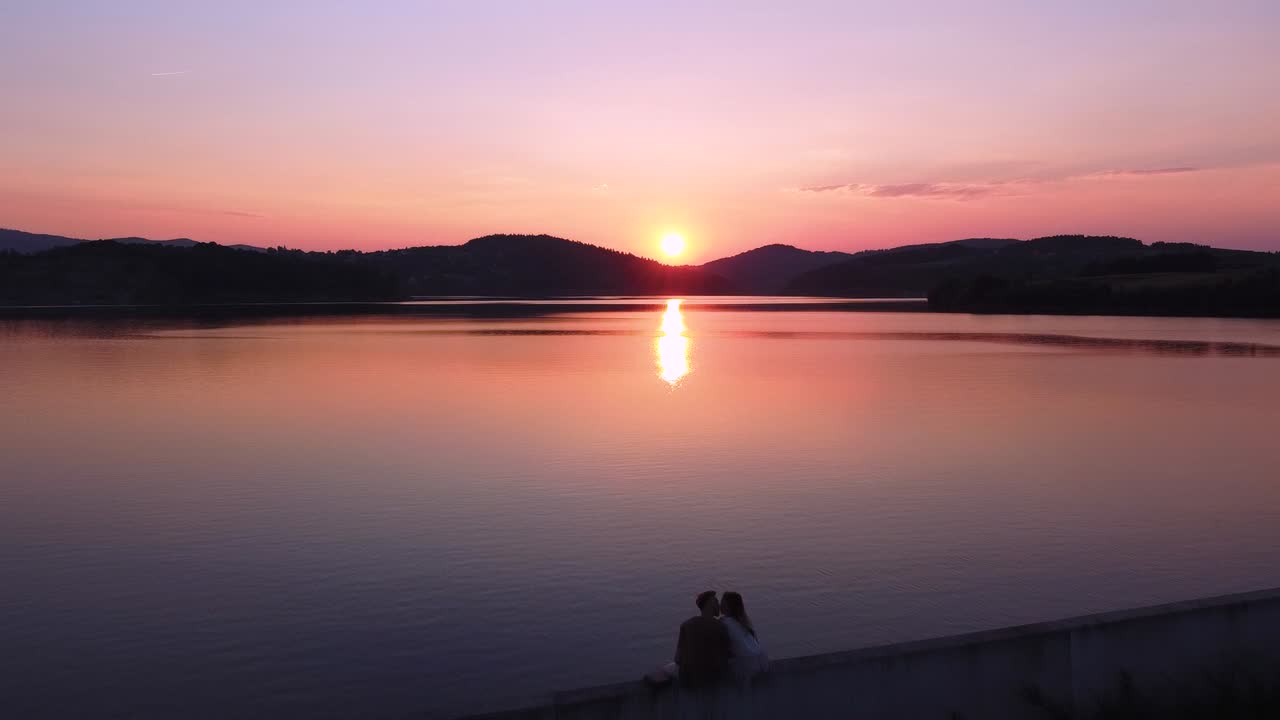 아름다운 일몰 동안 호수 옆에서 키스하는 커플