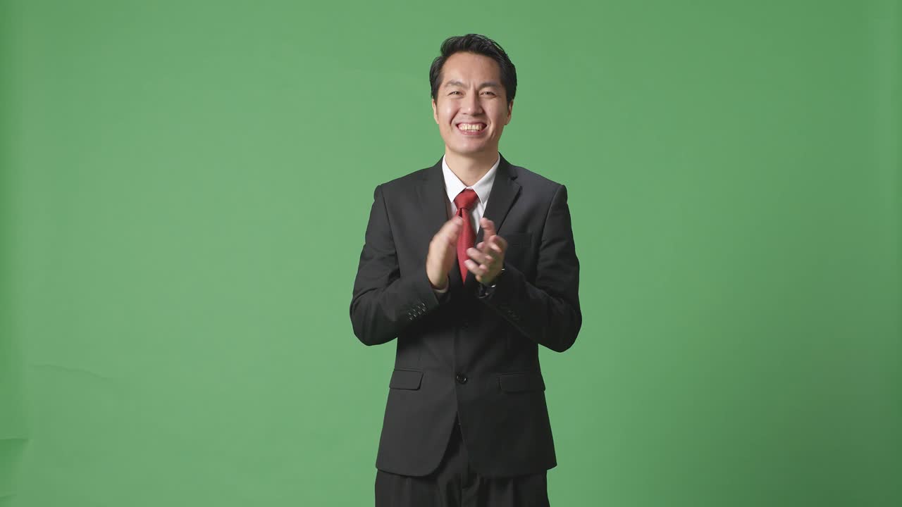 아시아 사업가 한 명 이 스튜디오 의 녹색 스크린 에서 인상적 인 손 을 박수 를 치고 있다