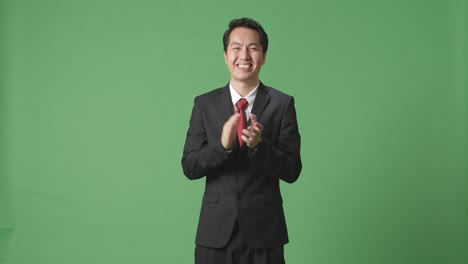 아시아 사업가 한 명 이 스튜디오 의 녹색 스크린 에서 인상적 인 손 을 박수 를 치고 있다