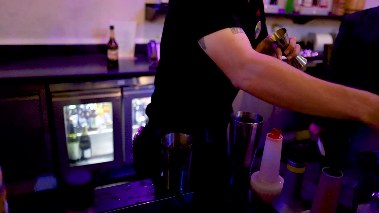Bartender stirs and mixes cocktail in dimly lit Bangkok bar using professional bar tools