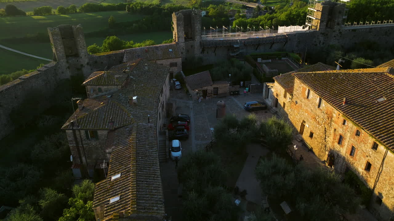 vuelo sobre la antigua ciudad amurallada de monteriggioni en toscana, italia al atardecer - disparo de drones