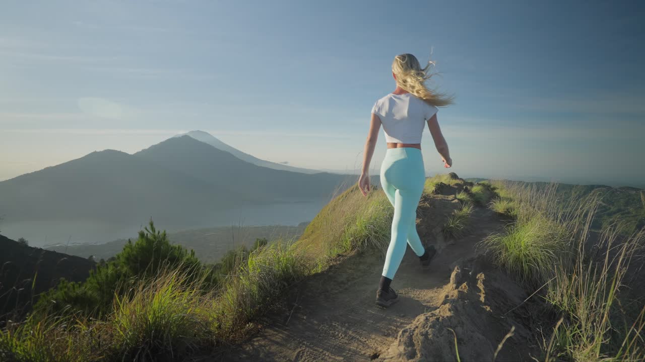 mujer caminando en la cresta del monte batur con vista de abang y agung durante el amanecer