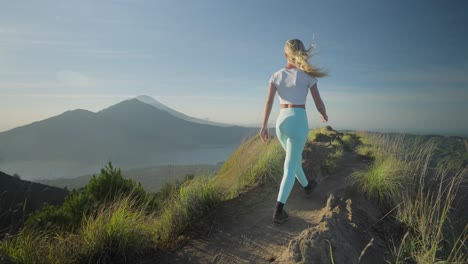 woman walking on ridge of mount batur with view of abang and agung during sunrise