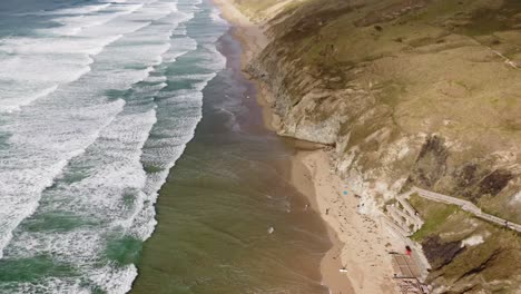 Una-Larga-Playa-De-Arena-Dorada-Con-Hermosas-Olas-Verdes-Rompiendo-En-Tierra-En-Cornualles