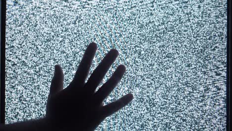 human hand touching old retro television screen with ripples, wavy flowing damaged signal. close-up of broken old-fashioned tv with noise, bad signal reception, cinematography concept