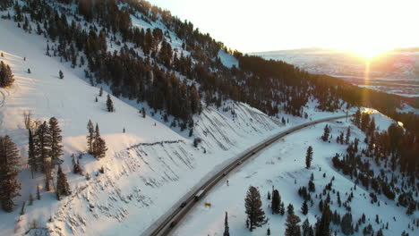 aerial view of teton pass highway on sunny winter evening, wyoming usa, traffic and snow capped hills