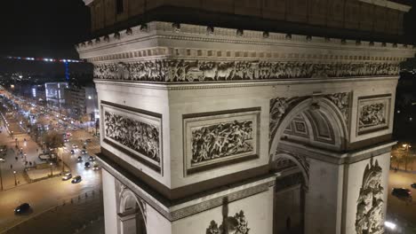 Drone-flying-near-Triumphal-Arch-or-Arc-de-Triomphe-illuminated-at-night,-Paris-in-France