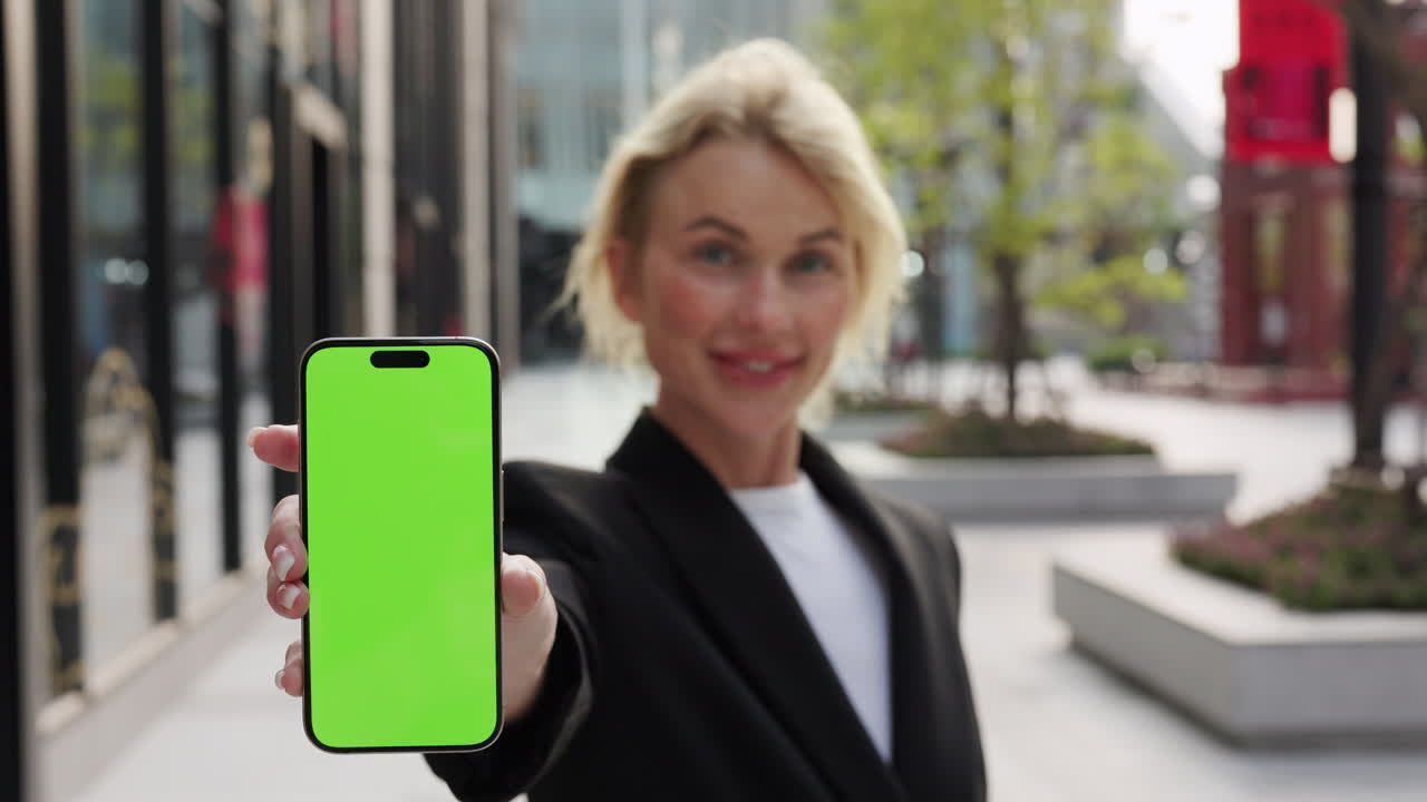 Woman showing a smartphone with a green screen