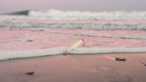 Fishing-lure-washed-up-on-a-beach-stuck-in-the-sand