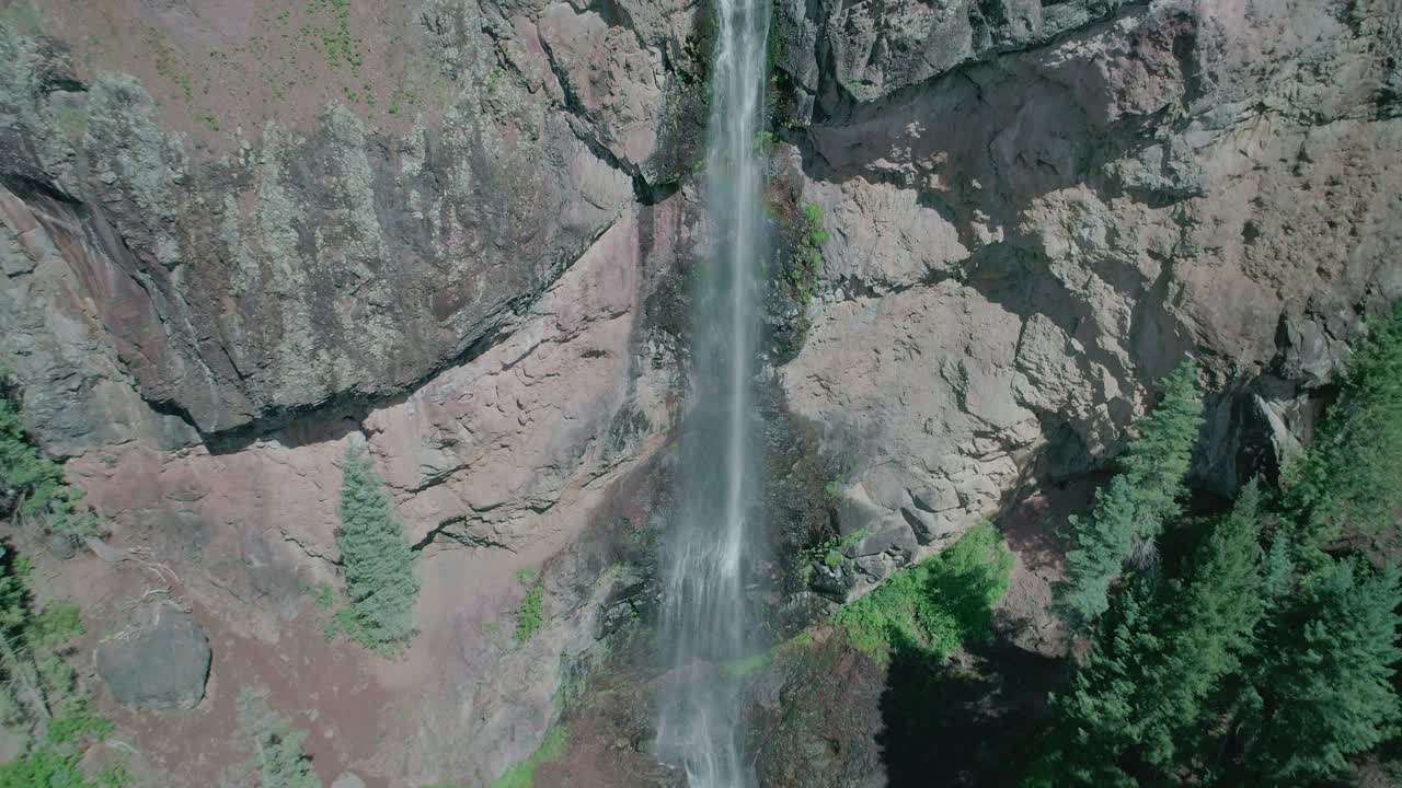 vista aérea de una gran cascada en una montaña rocosa con muchos pinos